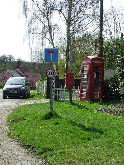 A red telephone box beside a red post box